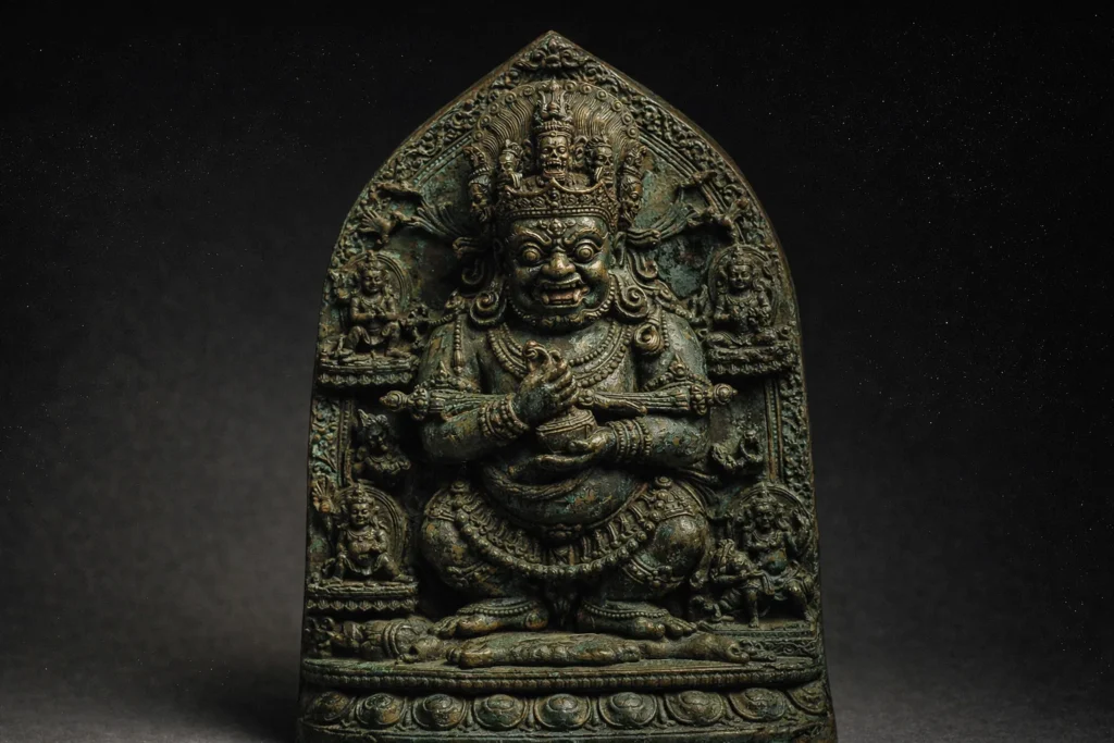 A dark, aged bronze statue of a stout, wrathful deity with multiple arms and a skull crown.