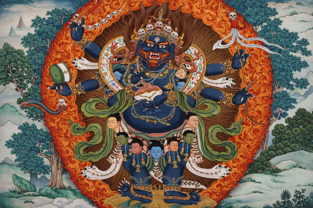 A six-armed blue deity with a skull crown standing before a ring of fire in a mountain landscape.