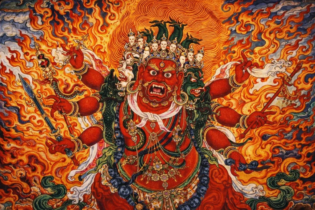 Multi-armed red deity with a crown of skulls surrounded by flames.