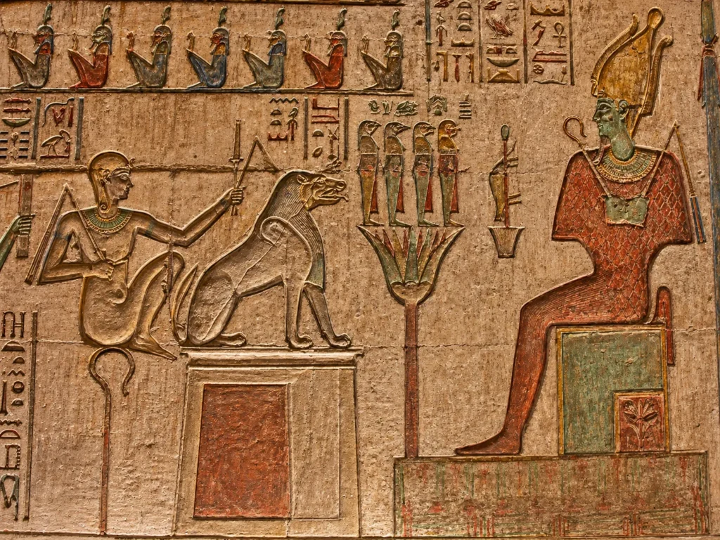 Detailed limestone relief of Ammit the Devourer seated before the throne of Osiris in the Egyptian underworld.